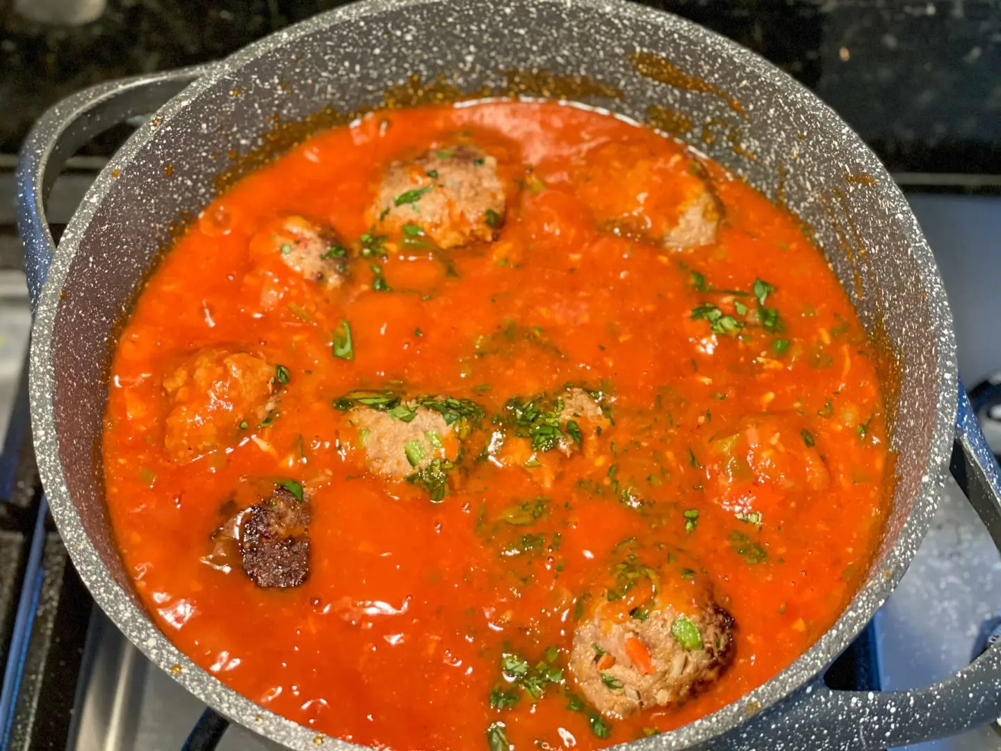 Photo of Cuban albondigas cooking in a sofrito sauce.