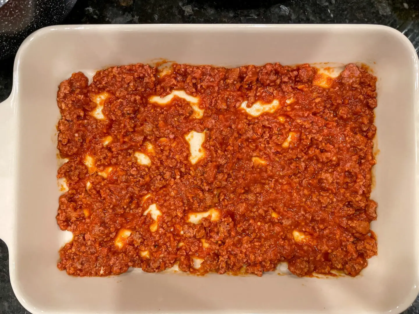 Spread meat sauce on the bottom of baking dish.