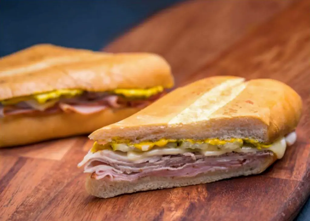 Cuban sandwich cut in half on a serving board from Porto’s Bakery.
