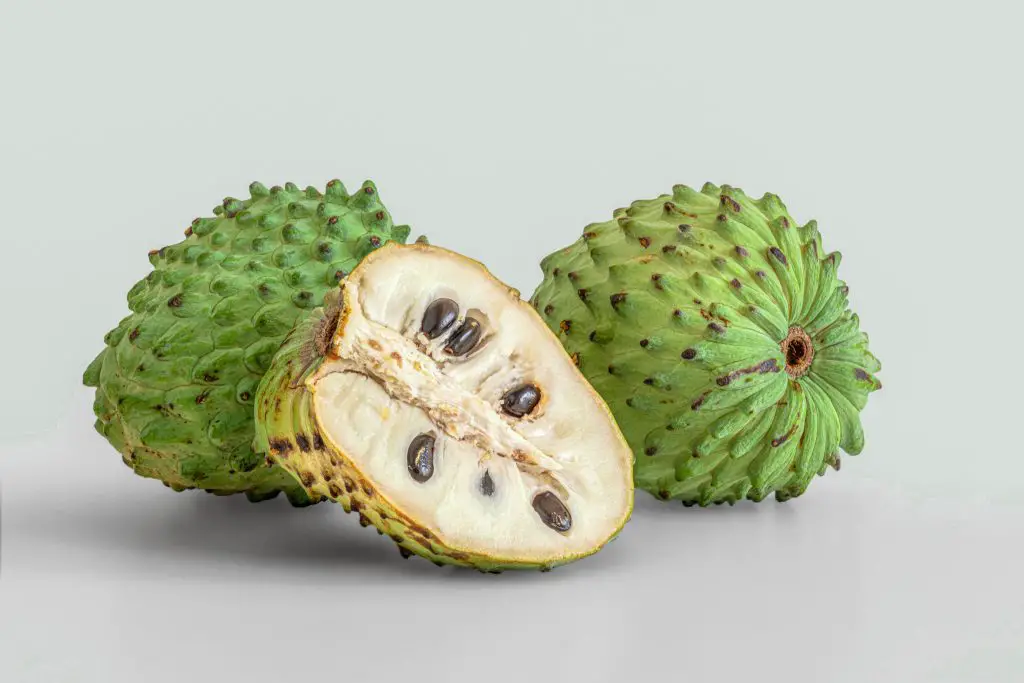 A guanabana cut in half showing the white creamy flesh.