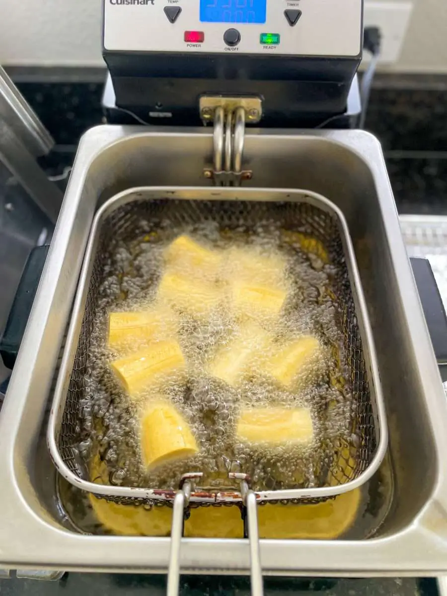 Frying thick-cut plantain bananas in a deep fryer.