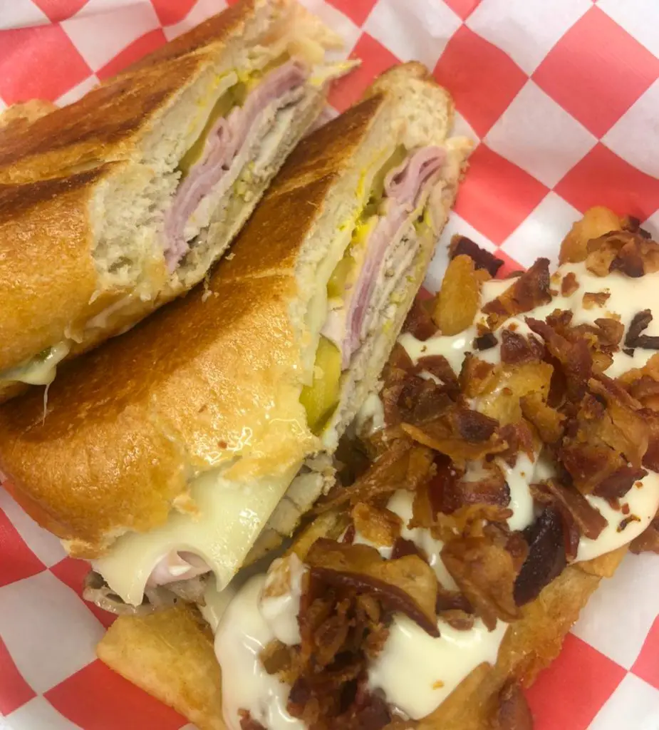 A Cuban sandwich served with loaded yuca fries from The Table Of Cuba.