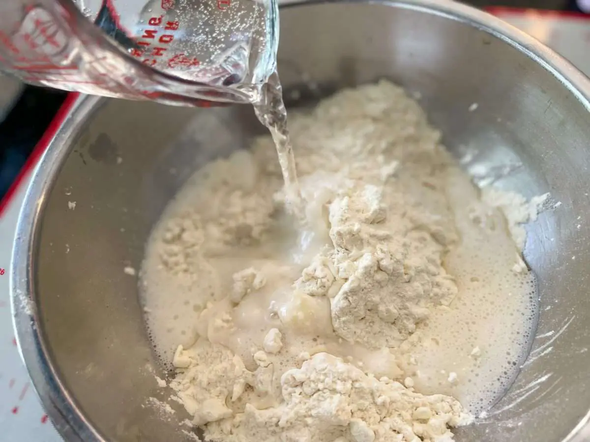 Adding sparkling water to empanada dough.