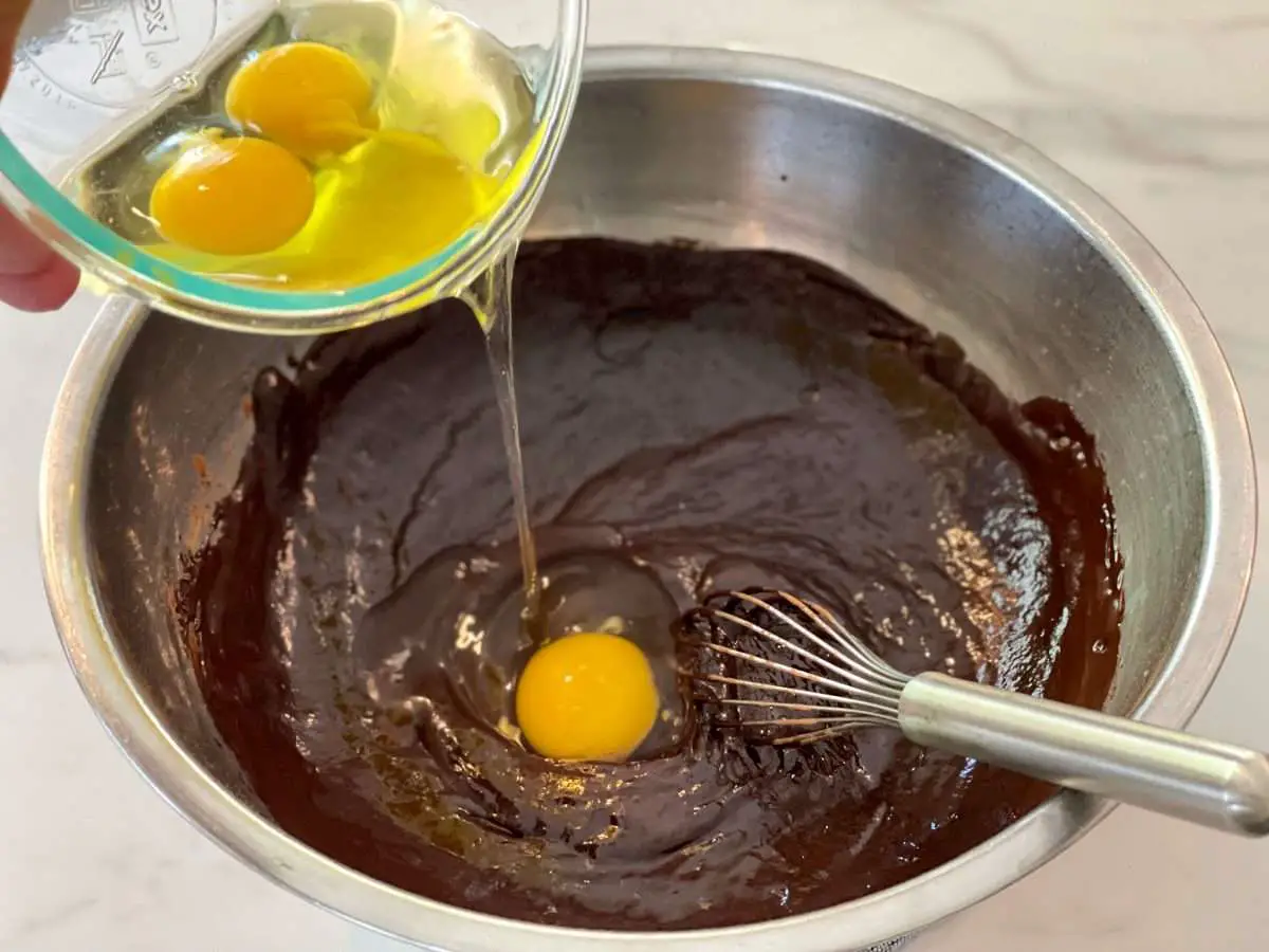 Adding eggs one at a time to chocolate mixture.