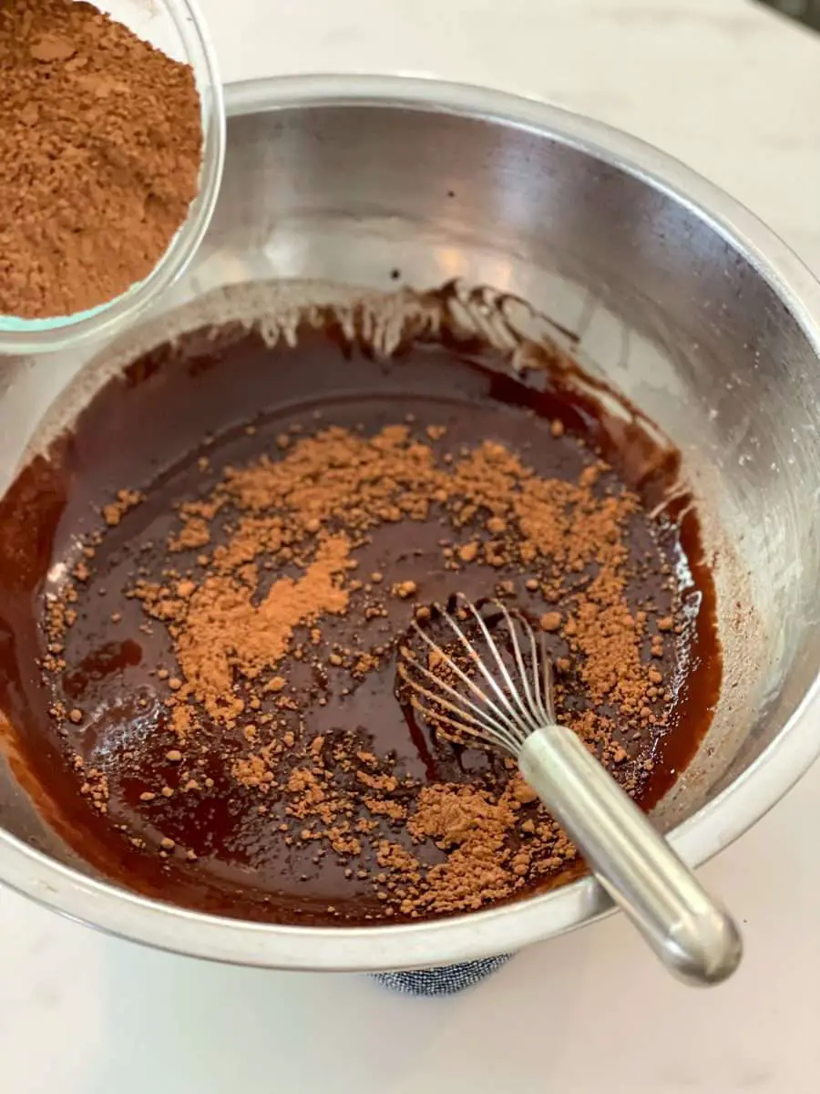 Adding cocoa powder to melted chocolate and butter.