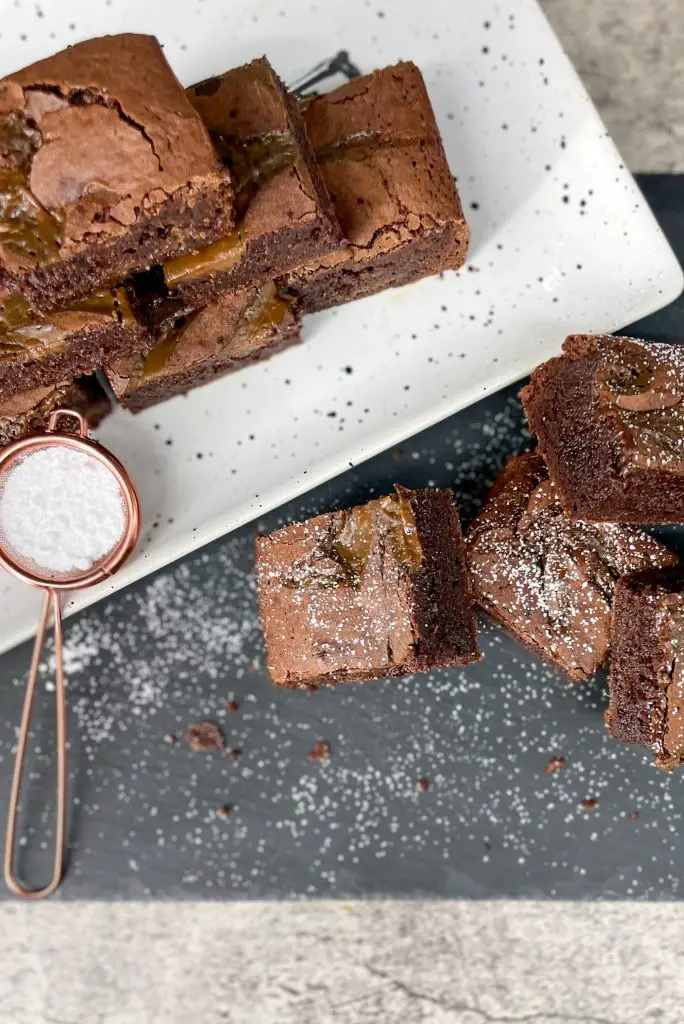 Brownies on a serving tray sprinkled with powdered sugar.