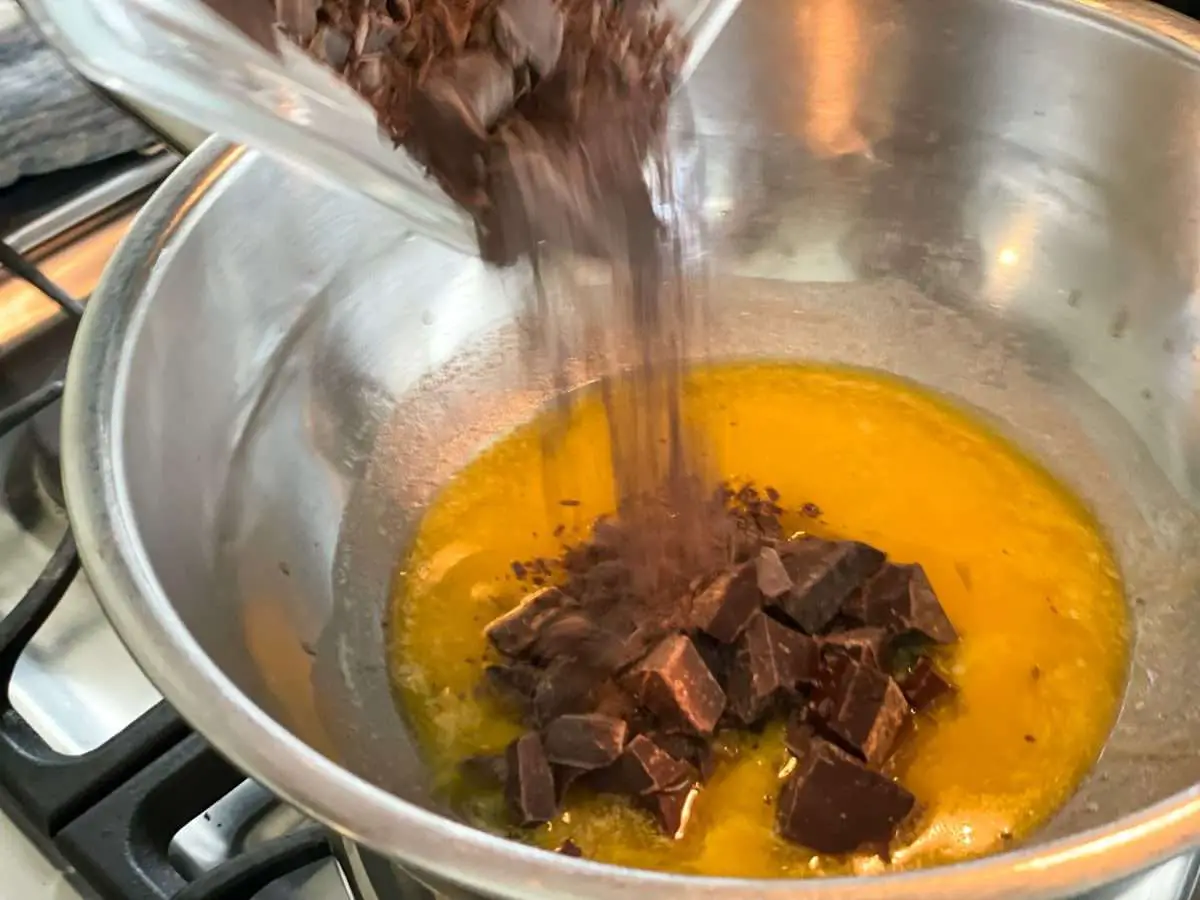 Adding chocolate to melted butter over a double broiler.