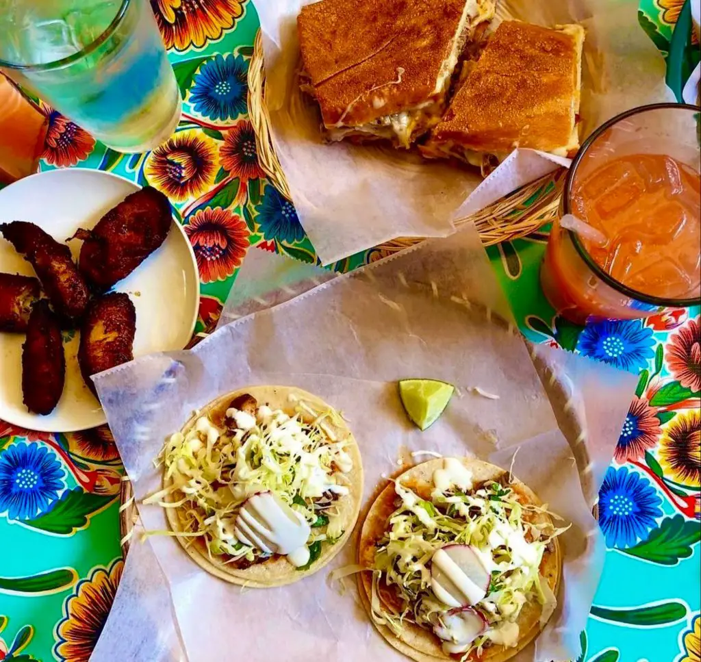 A display of fish tacos, maduros, a cuban sandwich and drinks from Cholita Linda restaurant.