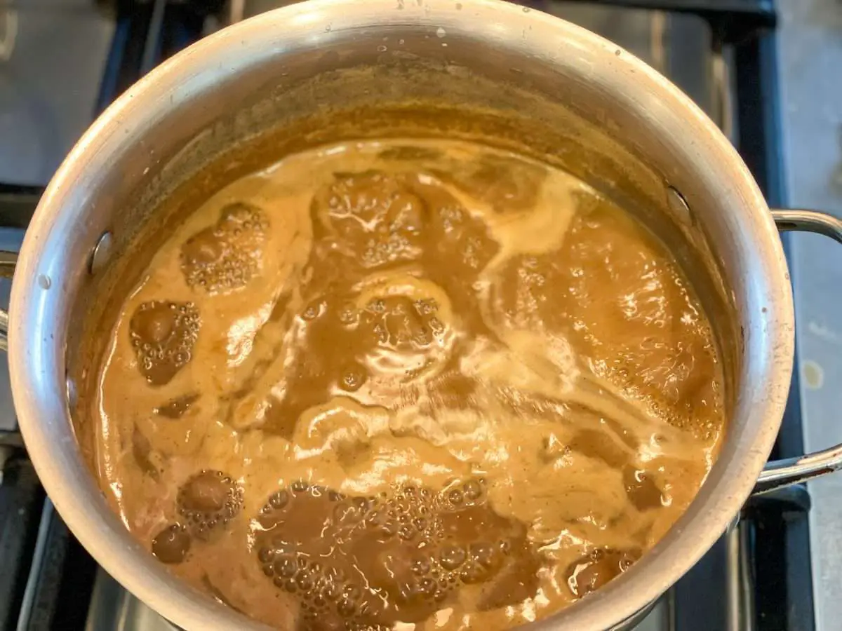 Simmering Dulce de leche in a pot on the stove during stage 2.