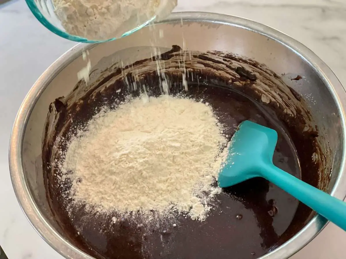 Adding flour to brownie batter.