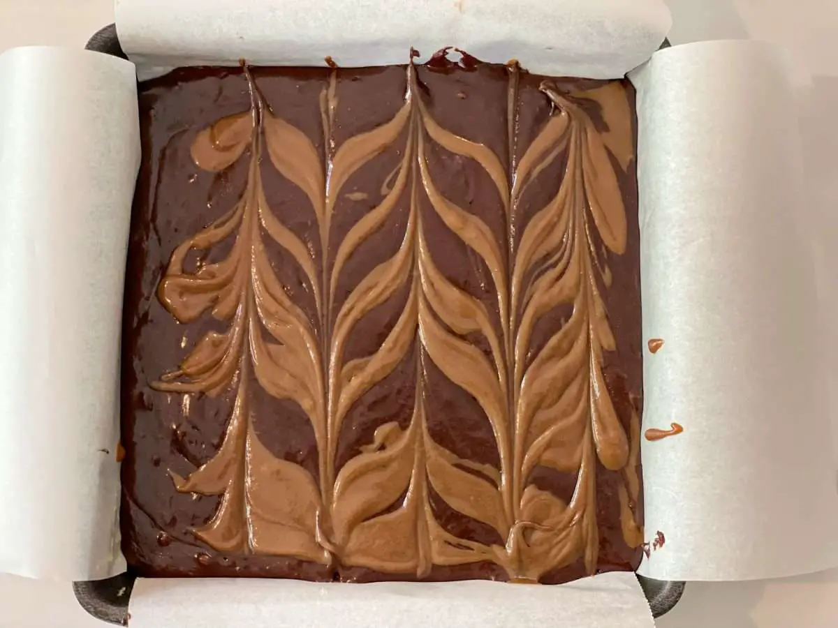 Dulce de leche brownies before it is cooked showing how to create the chevron pattern.
