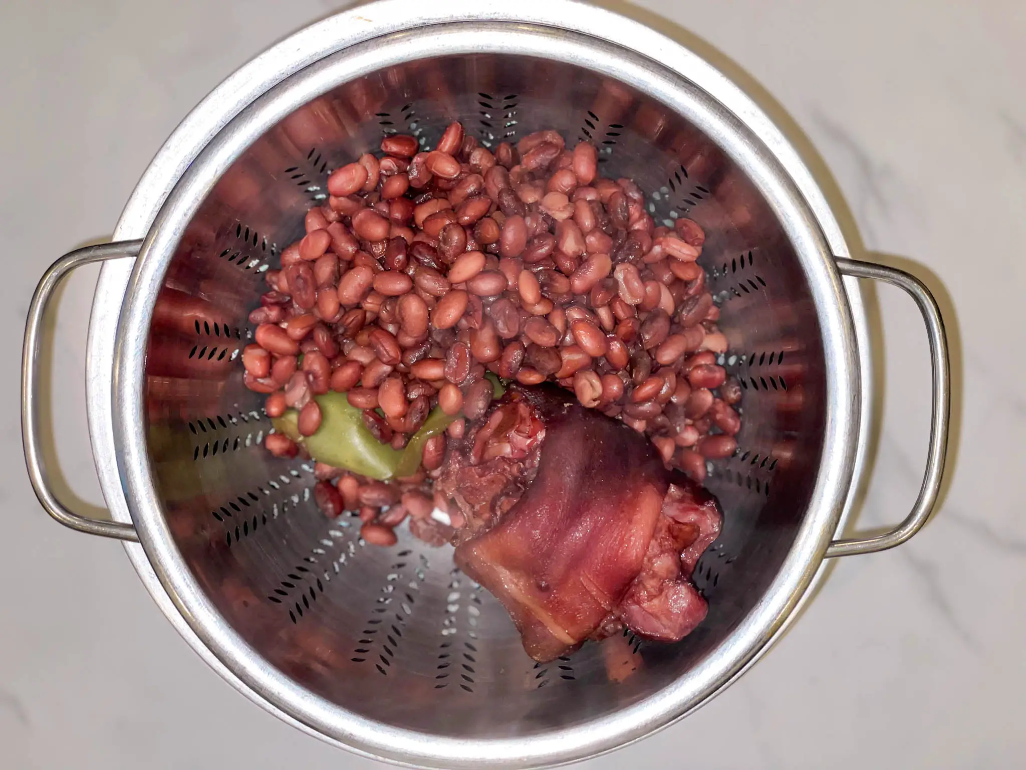 Draining red beans, hock and bell pepper in a colander.