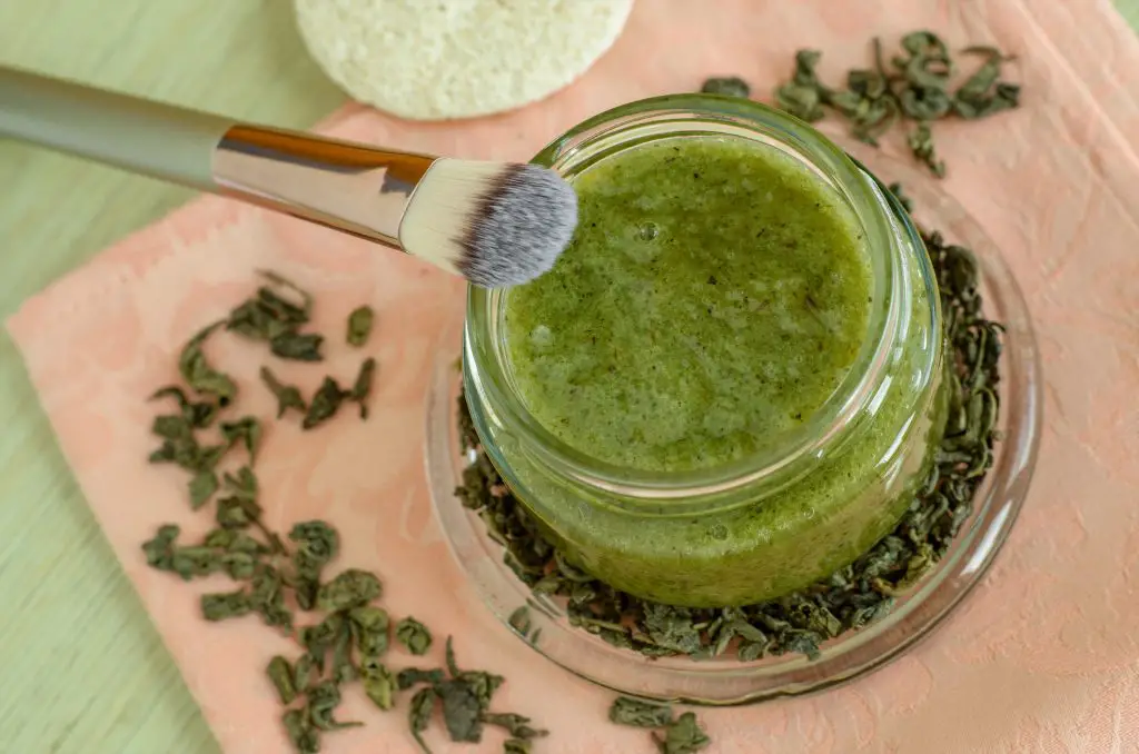 Homemade moringa oleifera natural face mask in a jar surrounded by moringa leaves.