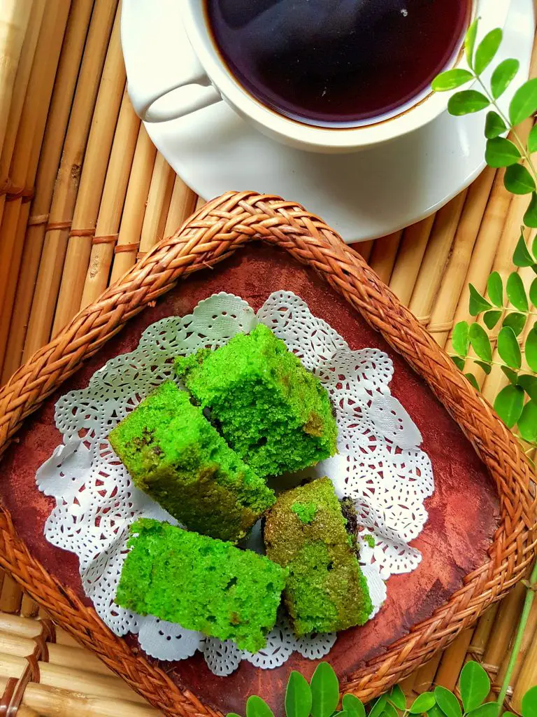 Moringa cake on a woven serving tray with a cup of coffee.