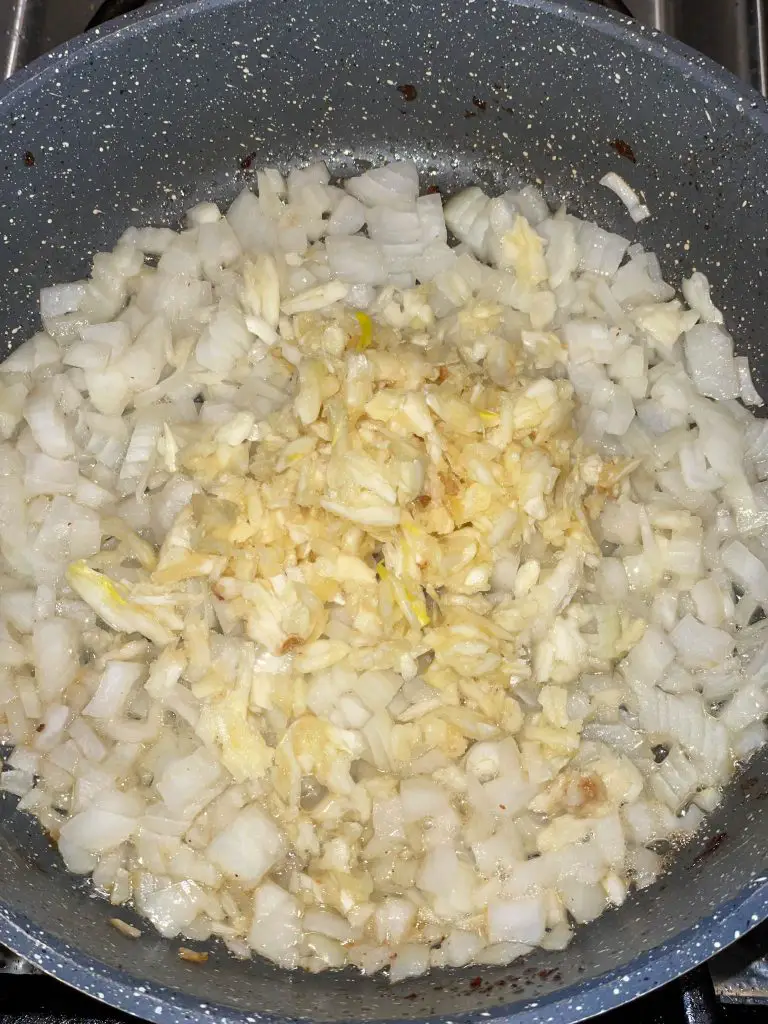 Sautéing onions and garlic in a sauté pan for red bean Congri.