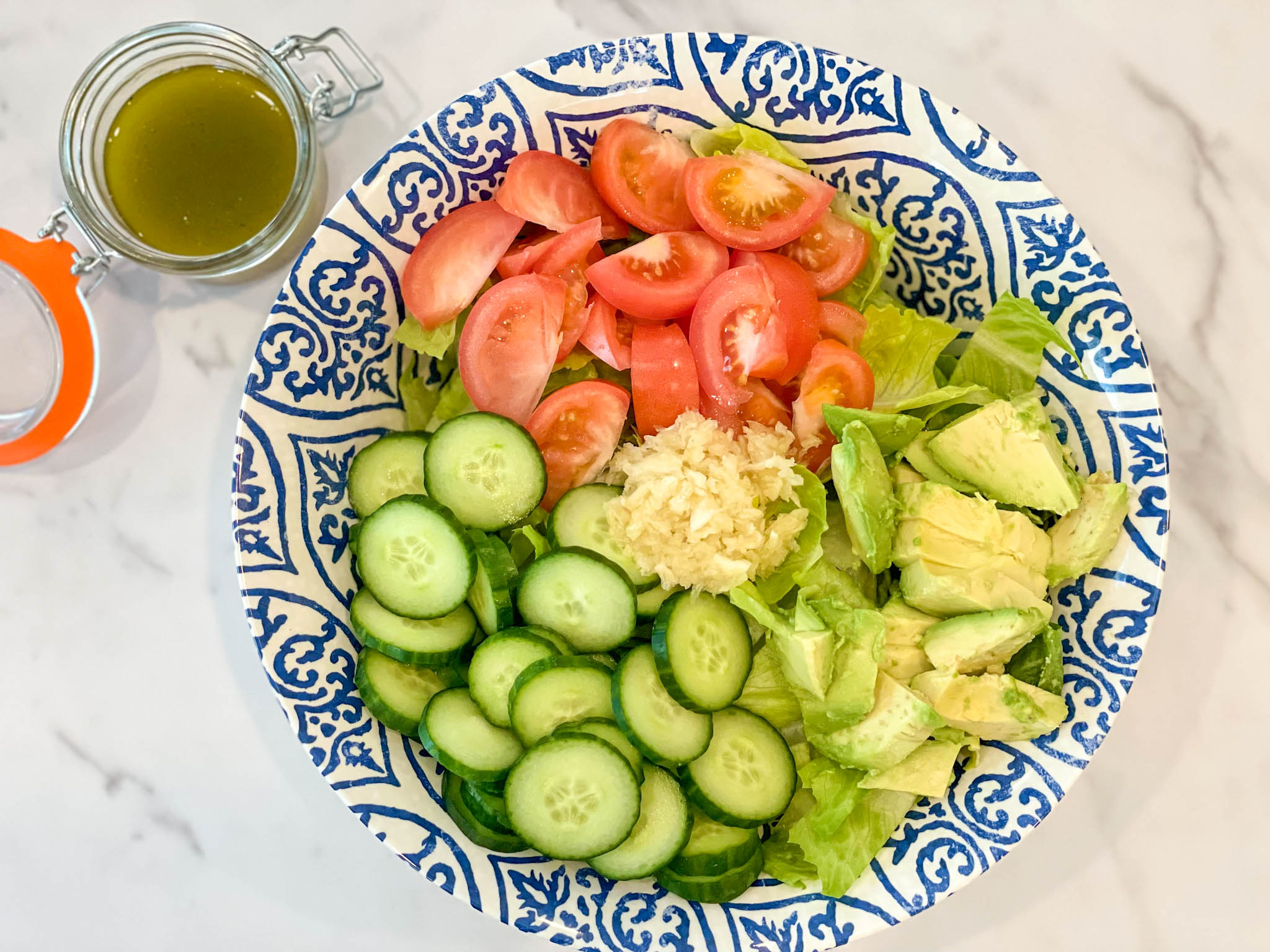 Ingredients such as tomatoes, cucumbers, avocado and fresh garlic to make a garden salad with a vinaigrette.