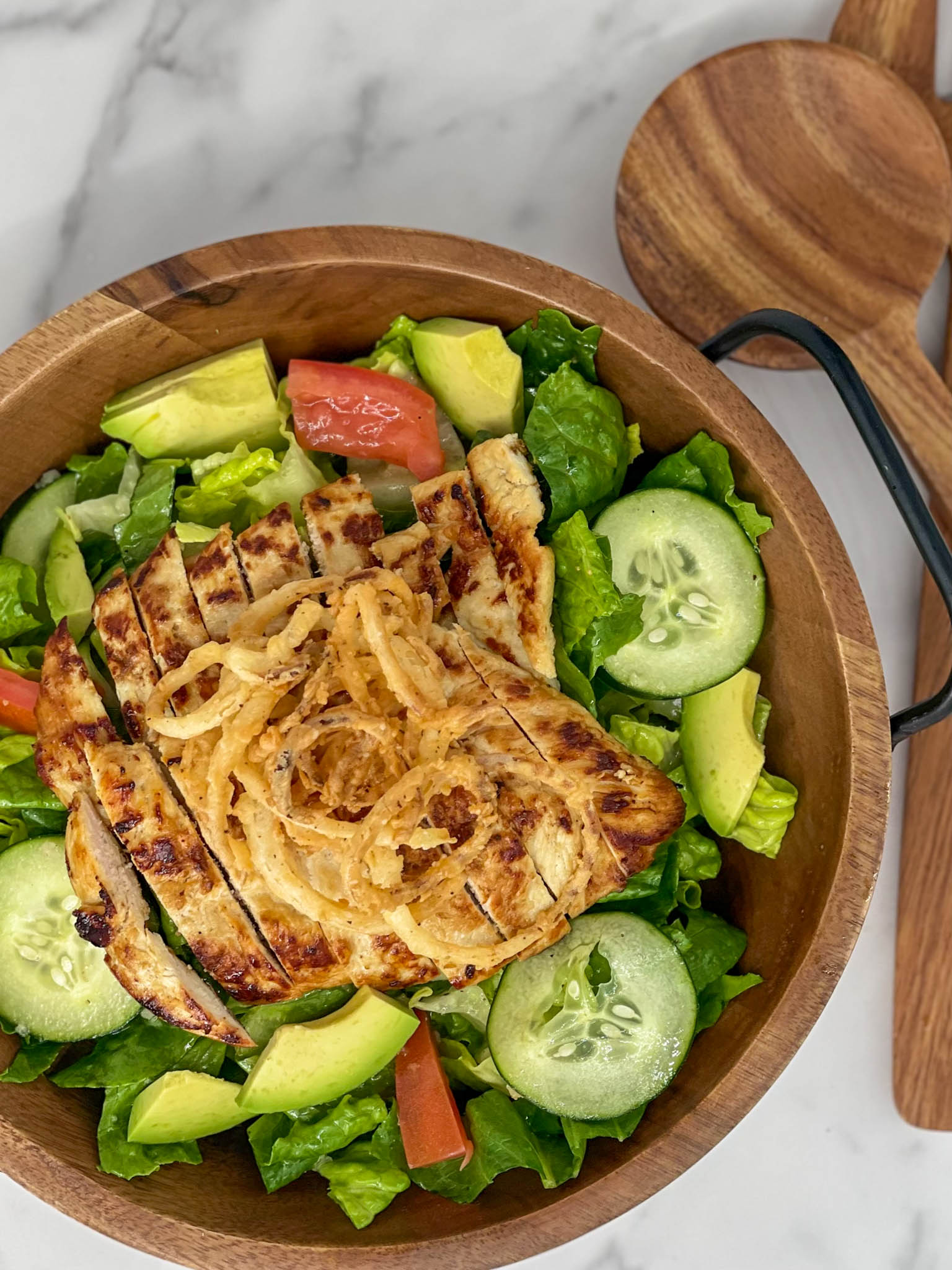 Fresh salad with grilled chicken served in a large wooden bowl.
