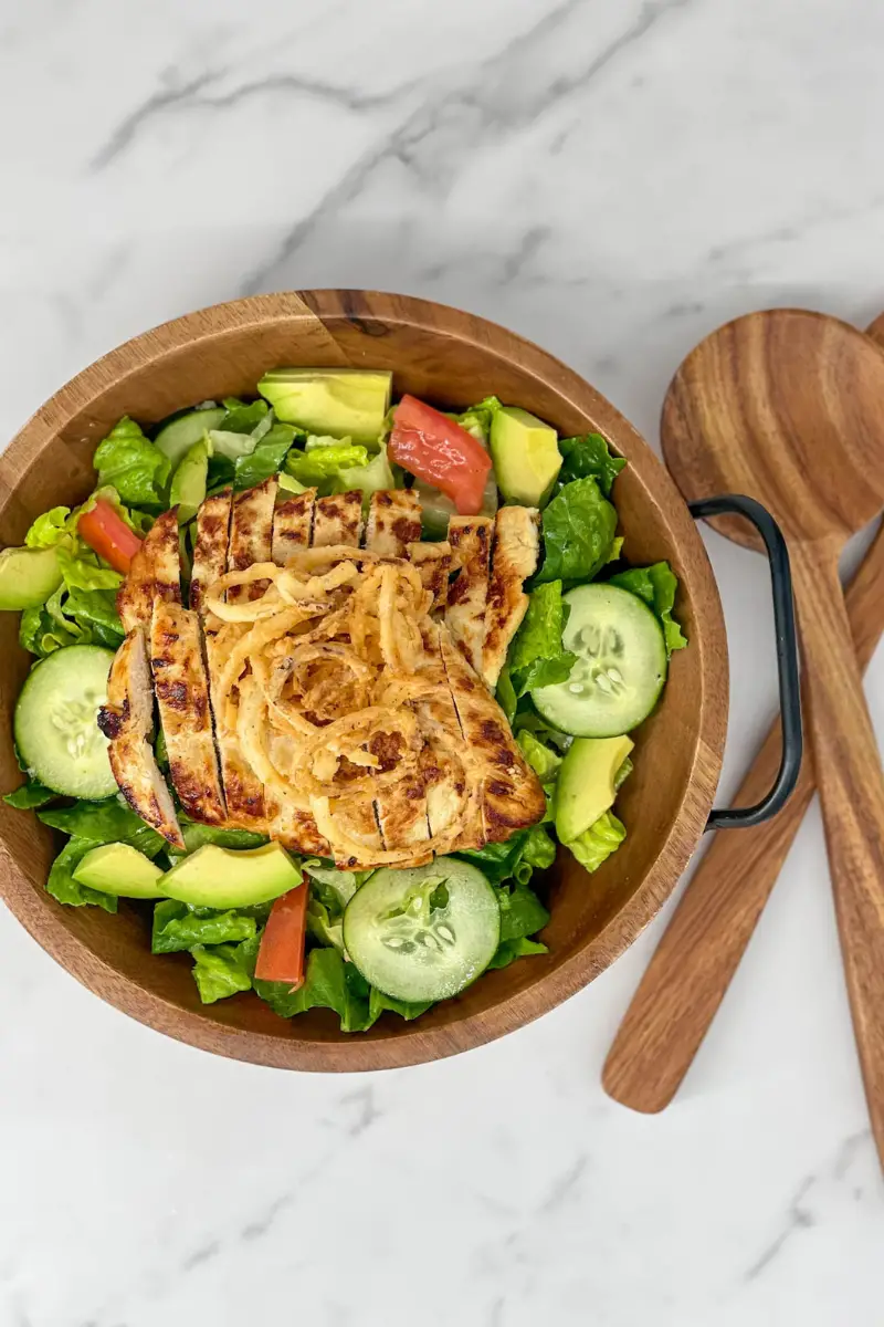 Ensalad con pollo in a large wooden bowl.