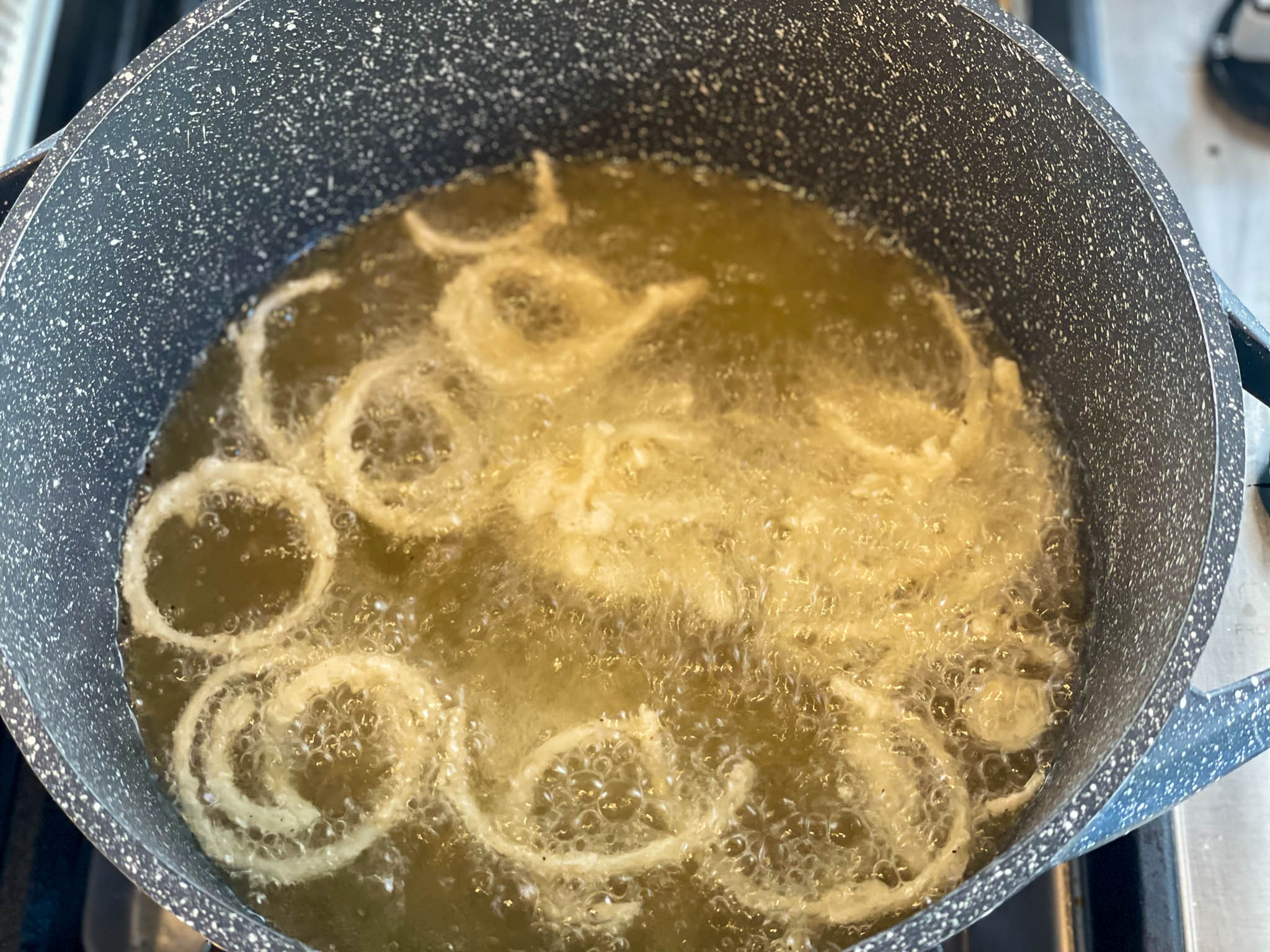 Onions frying in oil in a pot to be used as a topping for the ensalada con pollo.