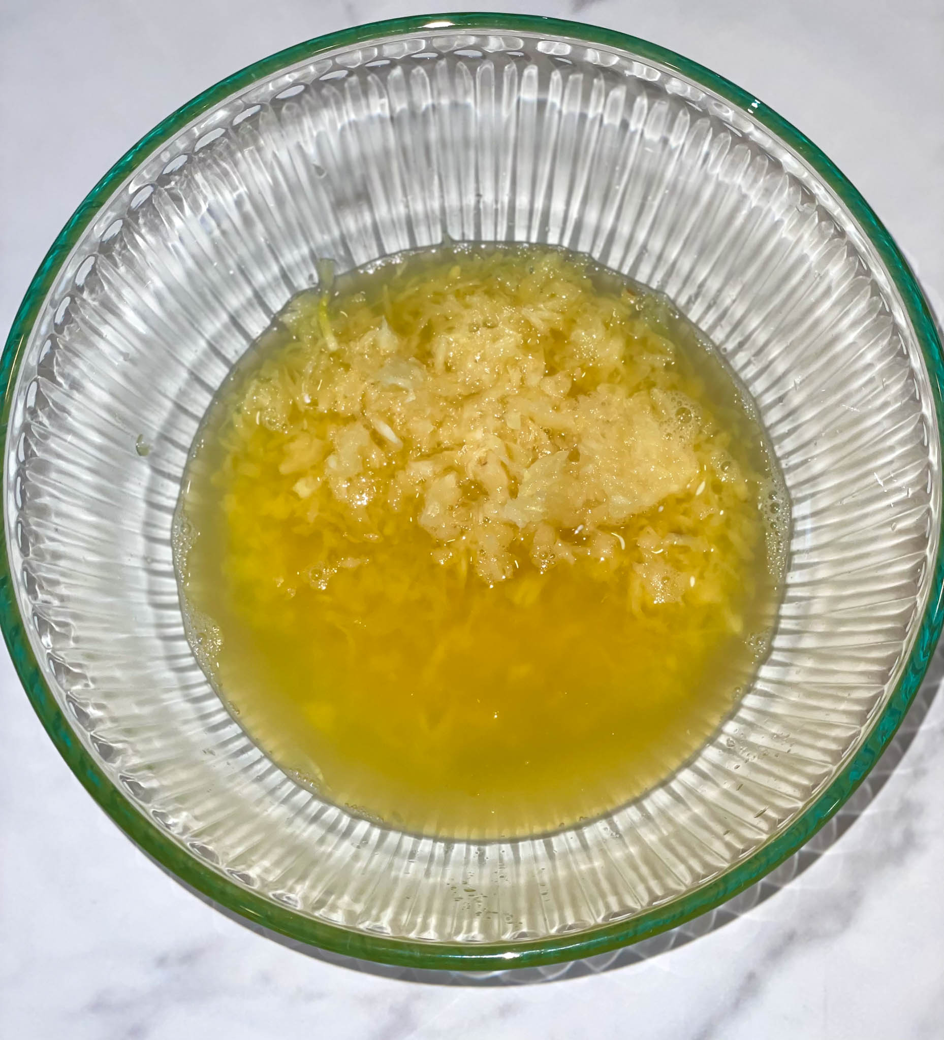 A marinade consisting of naranja agria, lime juice, garlic and salt for pollo in a glass bowl on a white background.